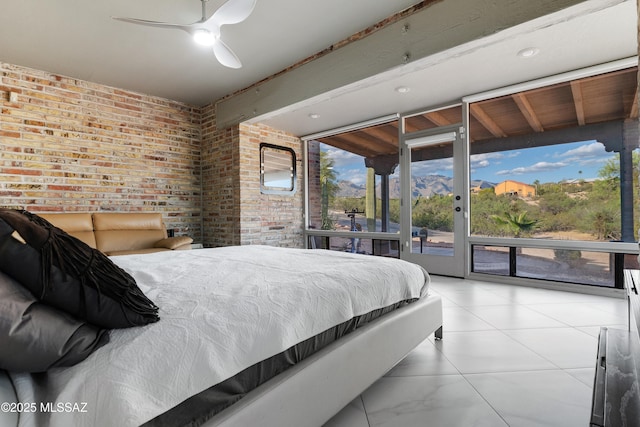 bedroom with access to exterior, expansive windows, brick wall, and ceiling fan