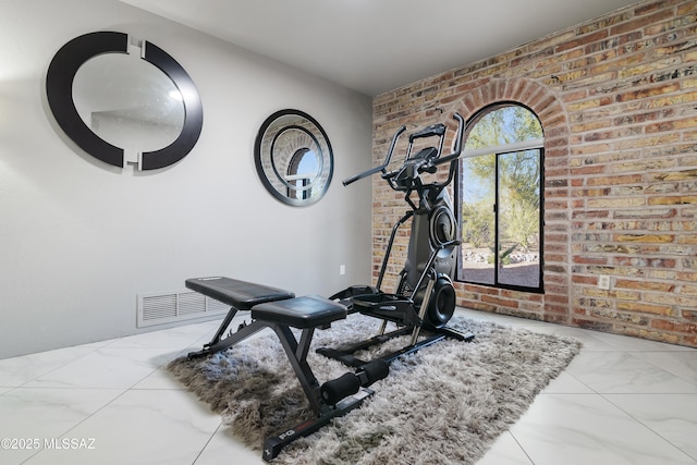 workout area with visible vents, marble finish floor, and brick wall