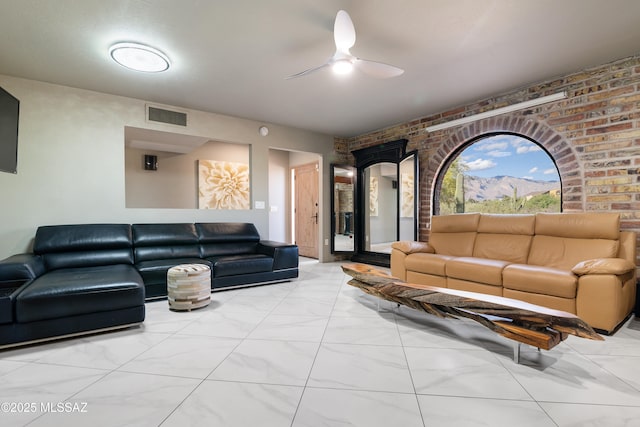 living room featuring visible vents, marble finish floor, brick wall, and a ceiling fan