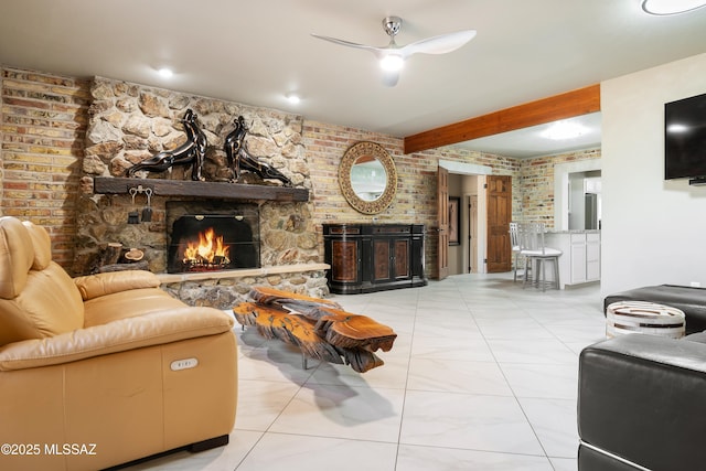 living room featuring brick wall, ceiling fan, beam ceiling, a stone fireplace, and light tile patterned flooring