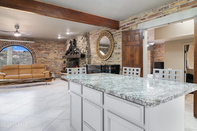 kitchen featuring brick wall, open floor plan, and a ceiling fan