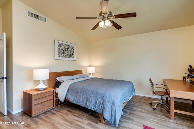 bedroom with vaulted ceiling, wood finished floors, visible vents, and baseboards