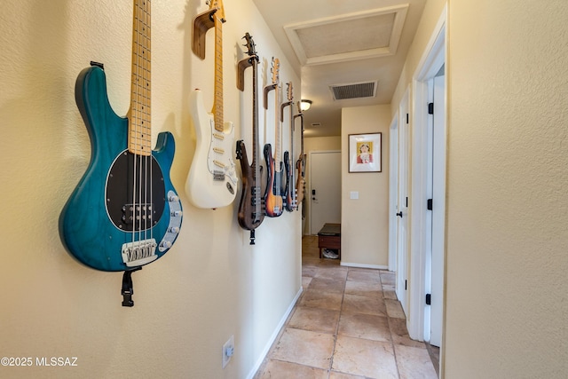 hall featuring attic access, baseboards, visible vents, and stone finish flooring