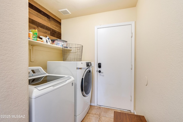 laundry room featuring laundry area, separate washer and dryer, visible vents, and wood walls