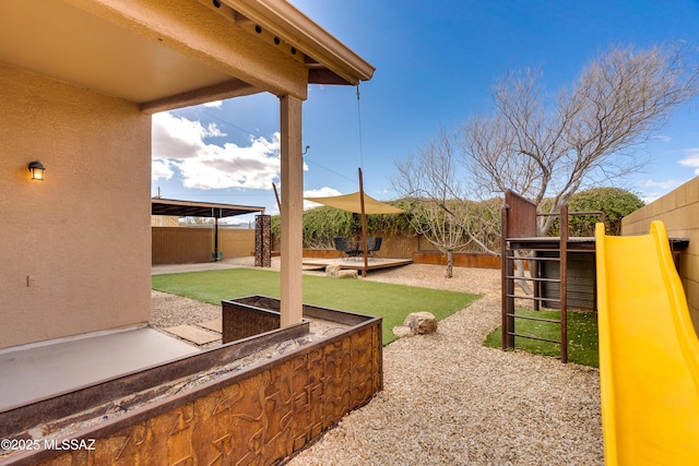 view of yard featuring a playground, a fenced backyard, and a patio area