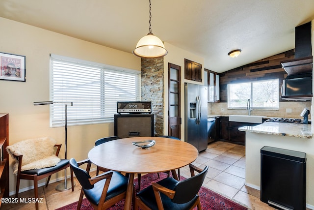 kitchen featuring tasteful backsplash, vaulted ceiling, stainless steel refrigerator with ice dispenser, stove, and a sink