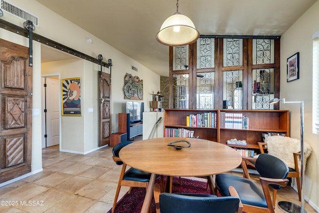 dining space featuring a barn door, baseboards, and visible vents