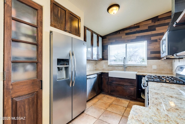 kitchen with a sink, decorative backsplash, vaulted ceiling, stainless steel appliances, and dark brown cabinets