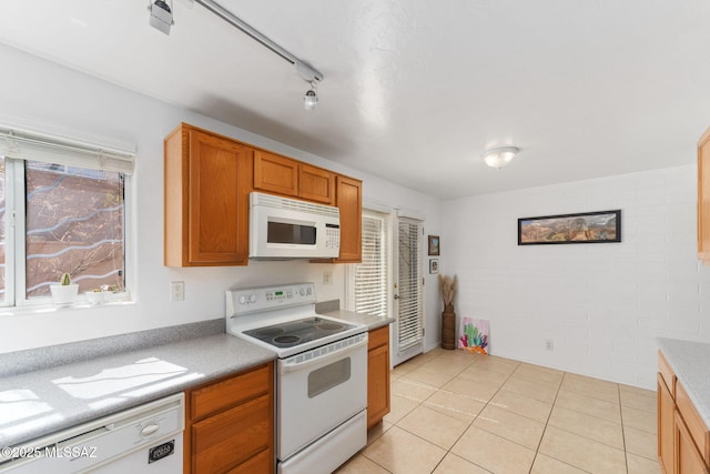 kitchen featuring light tile patterned flooring, brown cabinets, white appliances, and light countertops