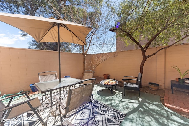 view of patio with a fire pit, outdoor dining area, and a fenced backyard