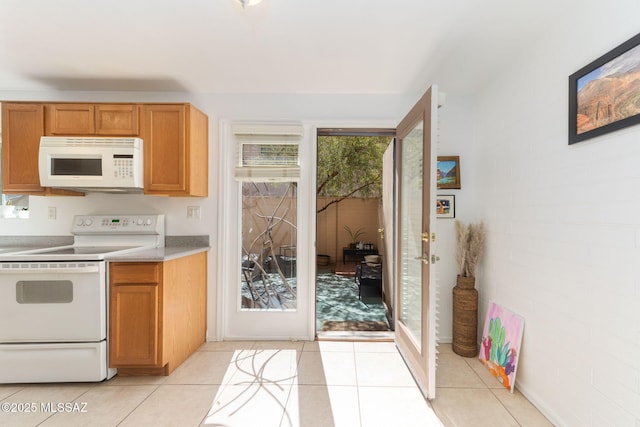 kitchen featuring white appliances, light tile patterned floors, light countertops, and brown cabinets