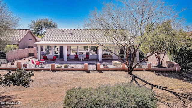 rear view of house featuring a patio, a fenced backyard, and a tile roof