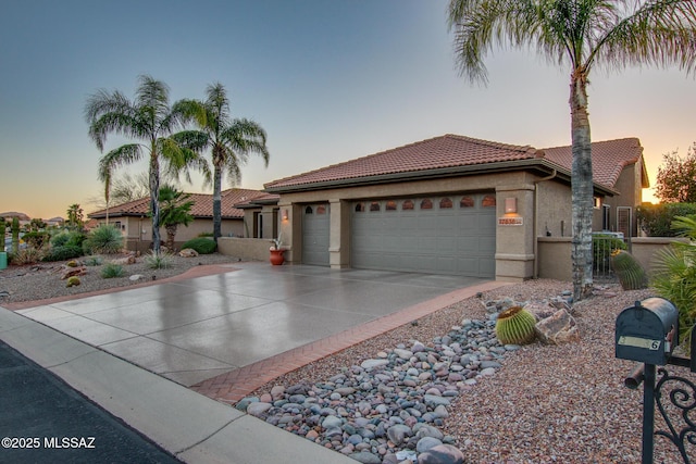 mediterranean / spanish-style home with stucco siding, driveway, an attached garage, and a tiled roof