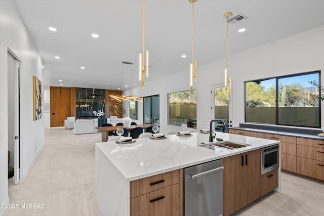 kitchen featuring visible vents, modern cabinets, a sink, open floor plan, and a large island with sink