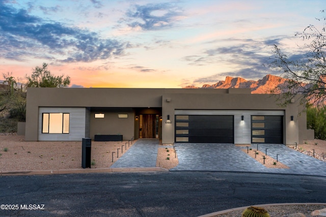 modern home featuring stucco siding, decorative driveway, and an attached garage