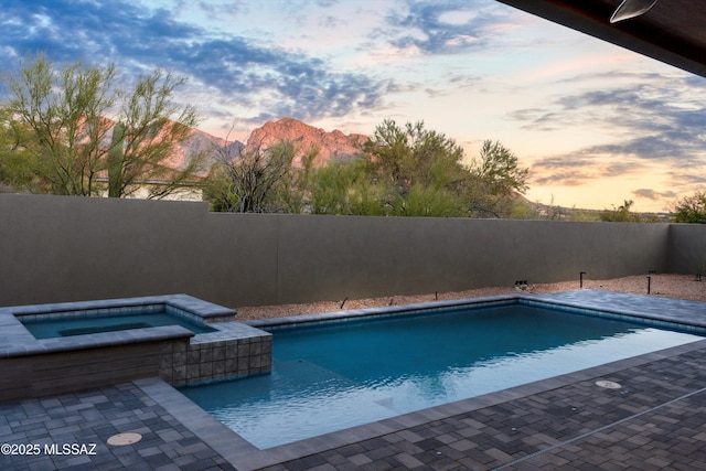 view of swimming pool with an in ground hot tub, a fenced in pool, a fenced backyard, and a mountain view