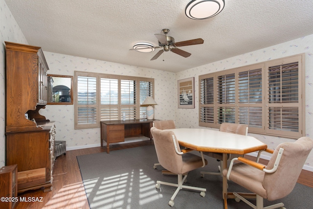 dining area with a textured ceiling, wallpapered walls, baseboards, and wood finished floors