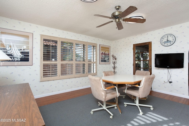 dining room featuring wallpapered walls, wood finished floors, and a textured ceiling