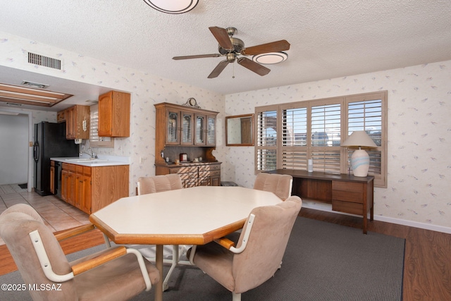 dining space featuring wallpapered walls, baseboards, visible vents, and a textured ceiling