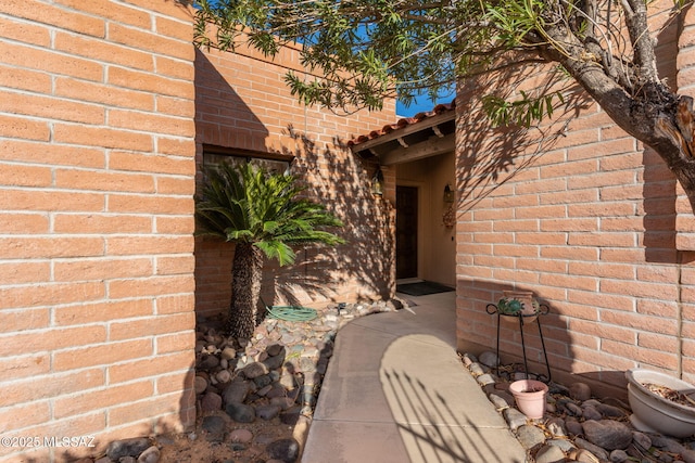 doorway to property featuring a tiled roof and brick siding