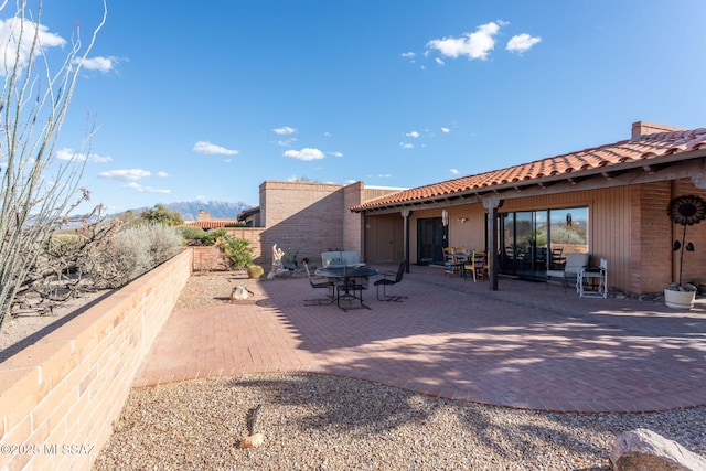 back of property with a patio, fence, and a tiled roof