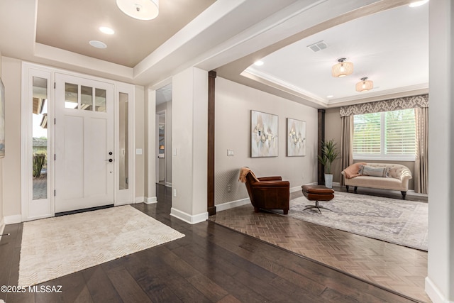 foyer entrance with visible vents, a raised ceiling, baseboards, and parquet flooring