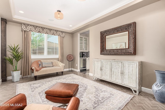 sitting room with recessed lighting, baseboards, a raised ceiling, and ornamental molding