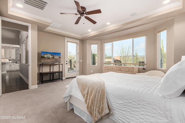 bedroom with access to exterior, visible vents, a tray ceiling, and ornamental molding