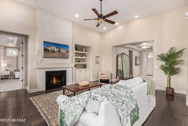 living area featuring dark wood finished floors, built in shelves, a fireplace, and baseboards