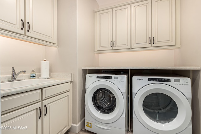 laundry room with cabinet space, washer and dryer, and a sink