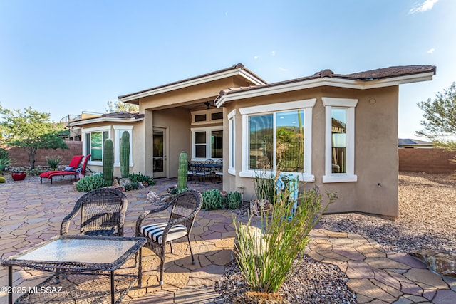 rear view of property with a patio area, stucco siding, and fence