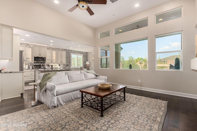 living area featuring recessed lighting, baseboards, dark wood-type flooring, and a ceiling fan