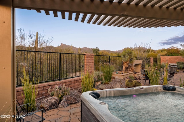 view of patio with a mountain view, fence, and a hot tub