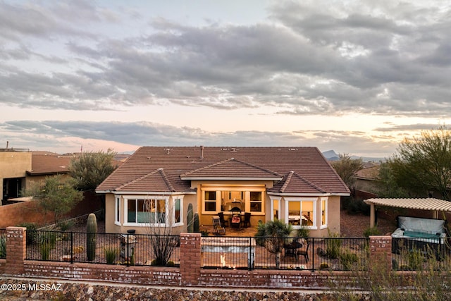 view of front of home with a patio area, stucco siding, a tiled roof, and fence private yard