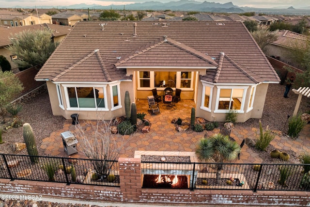 view of front facade featuring stucco siding, a patio, a mountain view, and fence