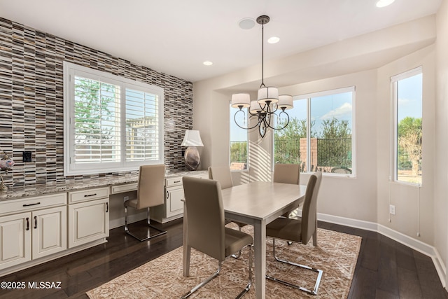 dining space featuring baseboards, dark wood finished floors, built in desk, recessed lighting, and an inviting chandelier