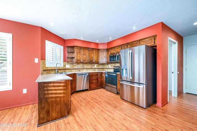 kitchen featuring light wood-style flooring, tasteful backsplash, open shelves, appliances with stainless steel finishes, and a sink