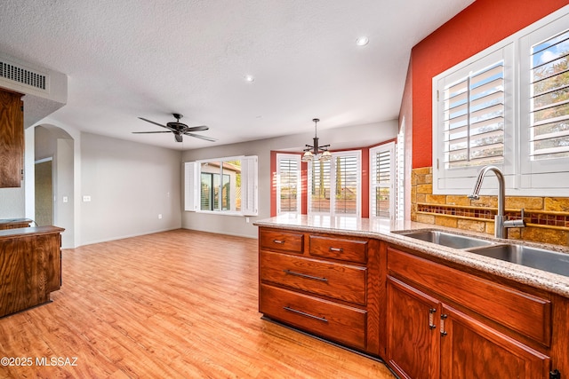 kitchen featuring light wood finished floors, visible vents, a sink, and backsplash