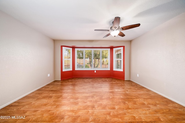 spare room featuring light wood finished floors, ceiling fan, and baseboards