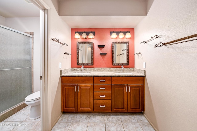 bathroom featuring toilet, double vanity, a sink, and a shower stall