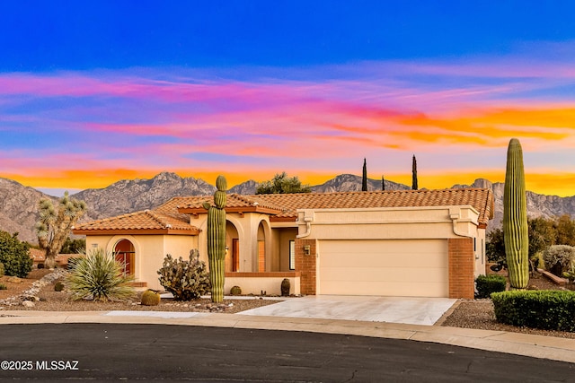 view of front facade featuring concrete driveway, stucco siding, a mountain view, an attached garage, and a tile roof