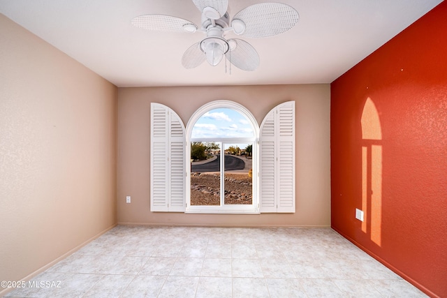 empty room with ceiling fan and baseboards