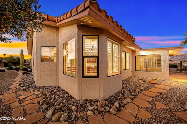 view of property exterior with a tiled roof and stucco siding