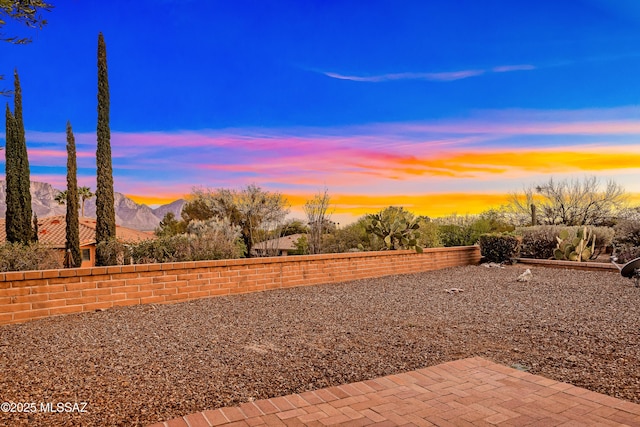 yard at dusk featuring a patio and a mountain view