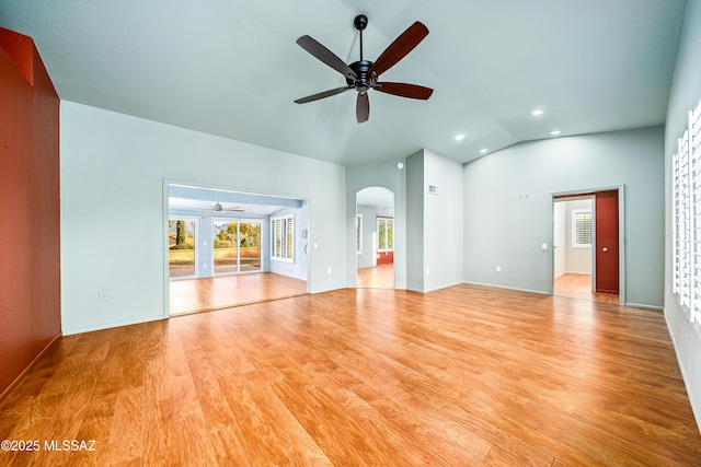 unfurnished living room featuring vaulted ceiling, recessed lighting, a ceiling fan, arched walkways, and wood finished floors