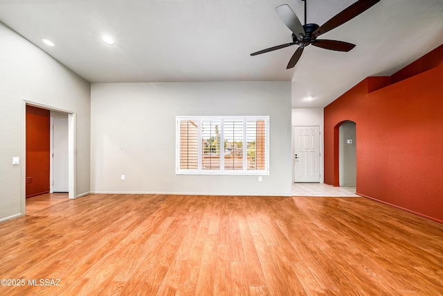 unfurnished living room with baseboards, arched walkways, ceiling fan, light wood-style floors, and recessed lighting