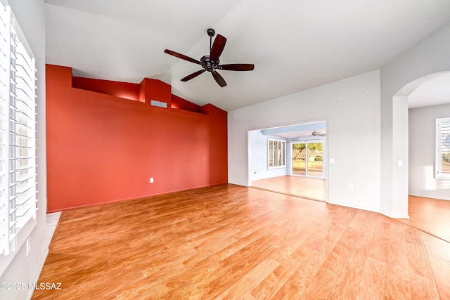 empty room featuring ceiling fan, arched walkways, wood finished floors, and lofted ceiling