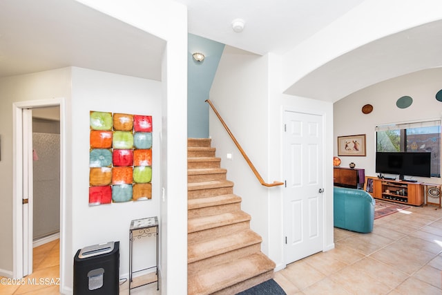 stairway featuring tile patterned floors and arched walkways