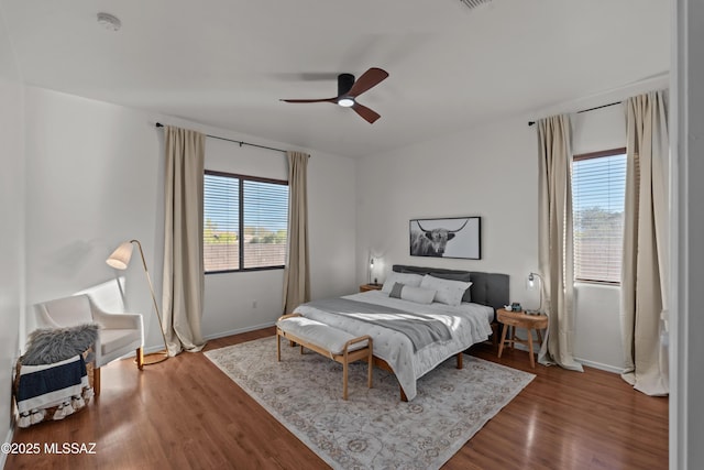 bedroom featuring visible vents, baseboards, ceiling fan, and wood finished floors