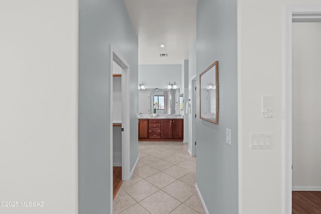 hallway featuring light tile patterned flooring, visible vents, and baseboards